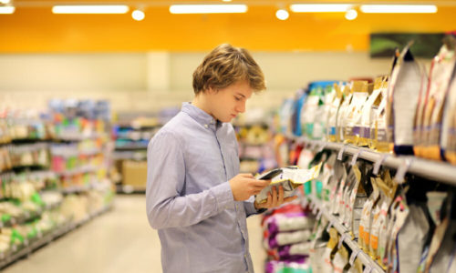 Guy looking at his phone in front of a pet food shelf